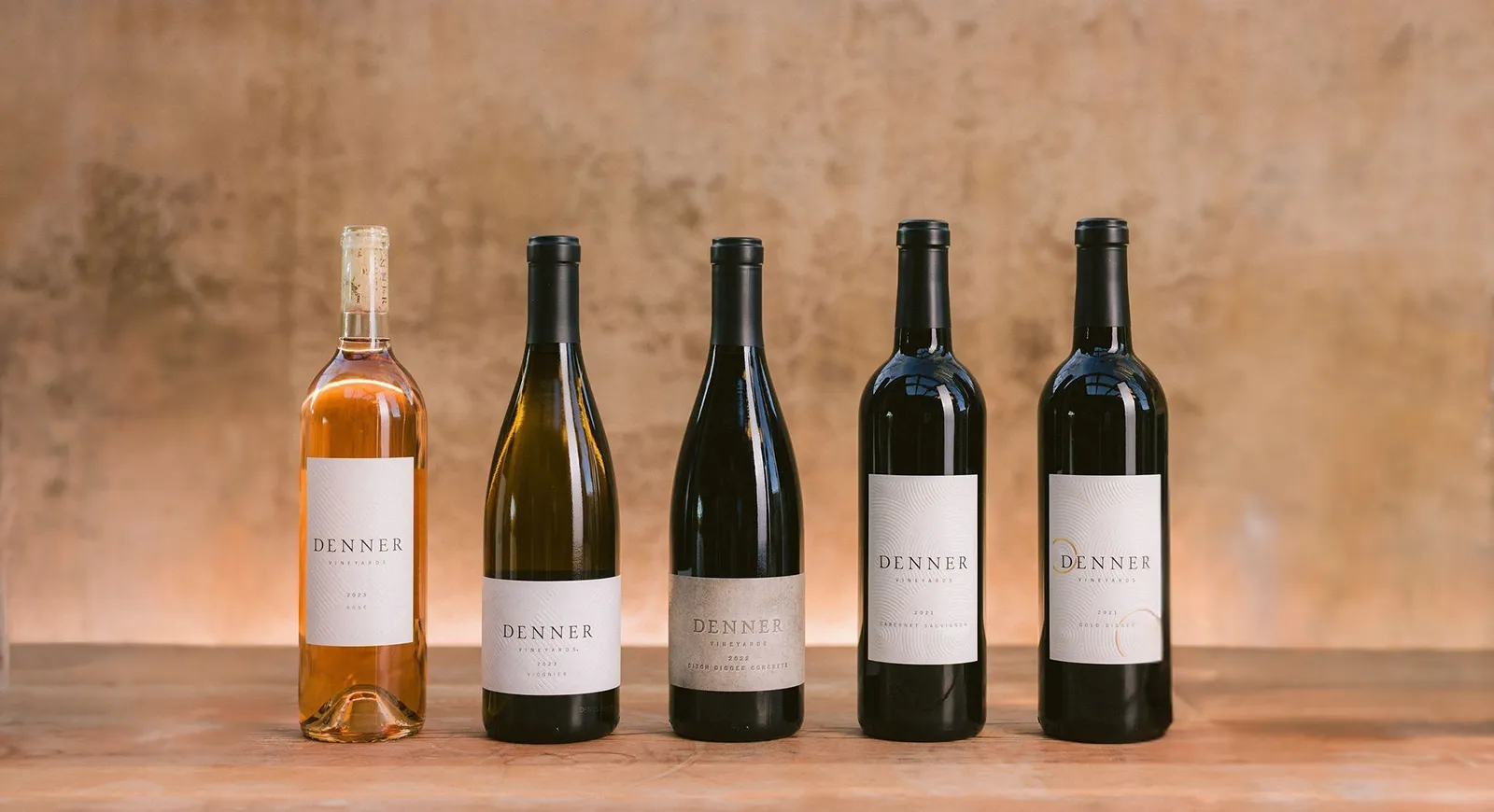 Denner wines, 5 bottle line up with a softly lit background.